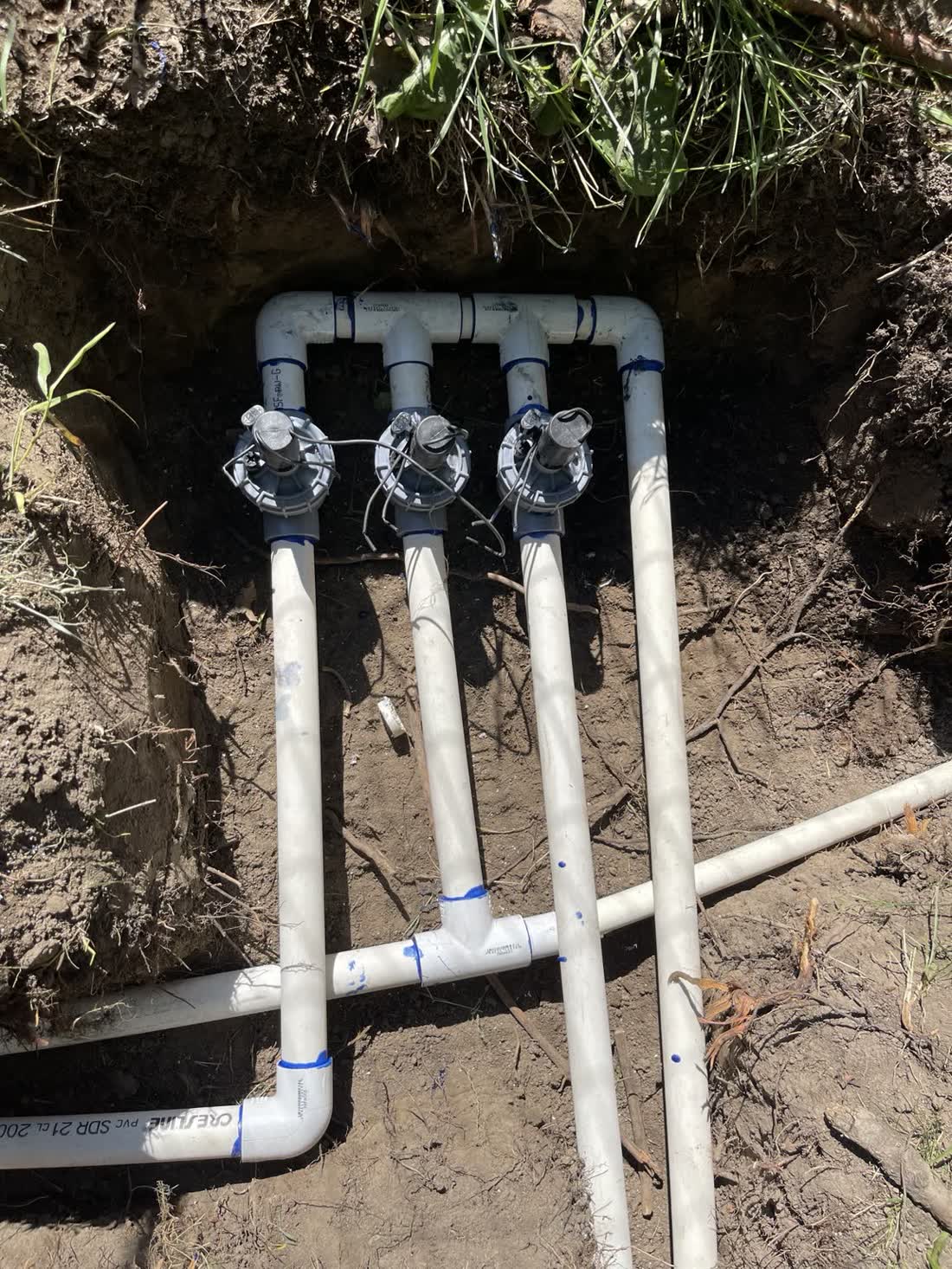 Three-valve PVC manifold tied into the mainline in a Benton City trench